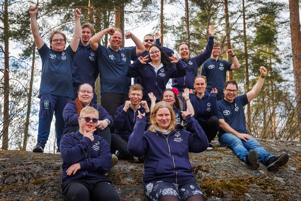Athlete Leaderit iloisessa yhteiskuvassa kalliolla, metsämaisemassa.